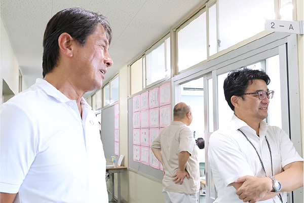 生徒のディスカッションを見つめる、当社 田中(左)と三島校長(右)